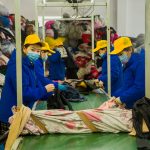 KingAAA worker sorting used clothing by category and grade at Guangzhou sorting facility.